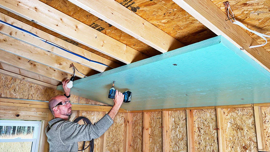 Person installing shed ceiling insulation using rigid foam board