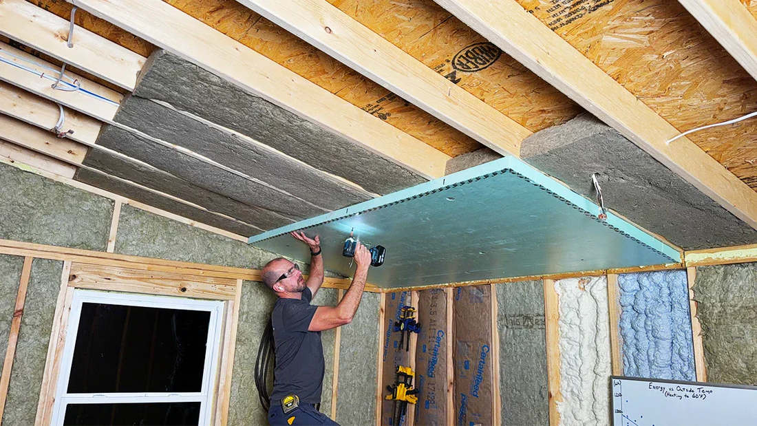 Person installing shed ceiling insulation with rigid foam board and Rockwool insulation