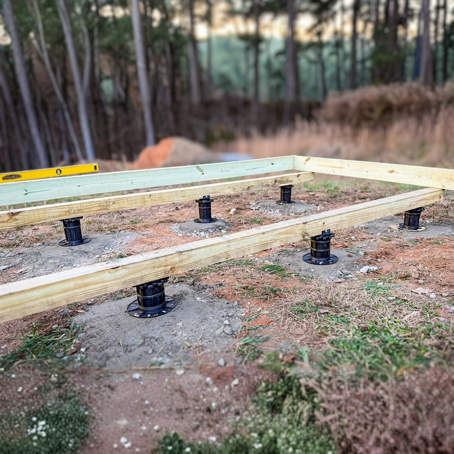Wooden beams with metal connectors on a construction site with trees in the background